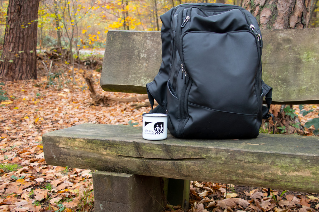 Tasse mit Rucksack auf einer Bank